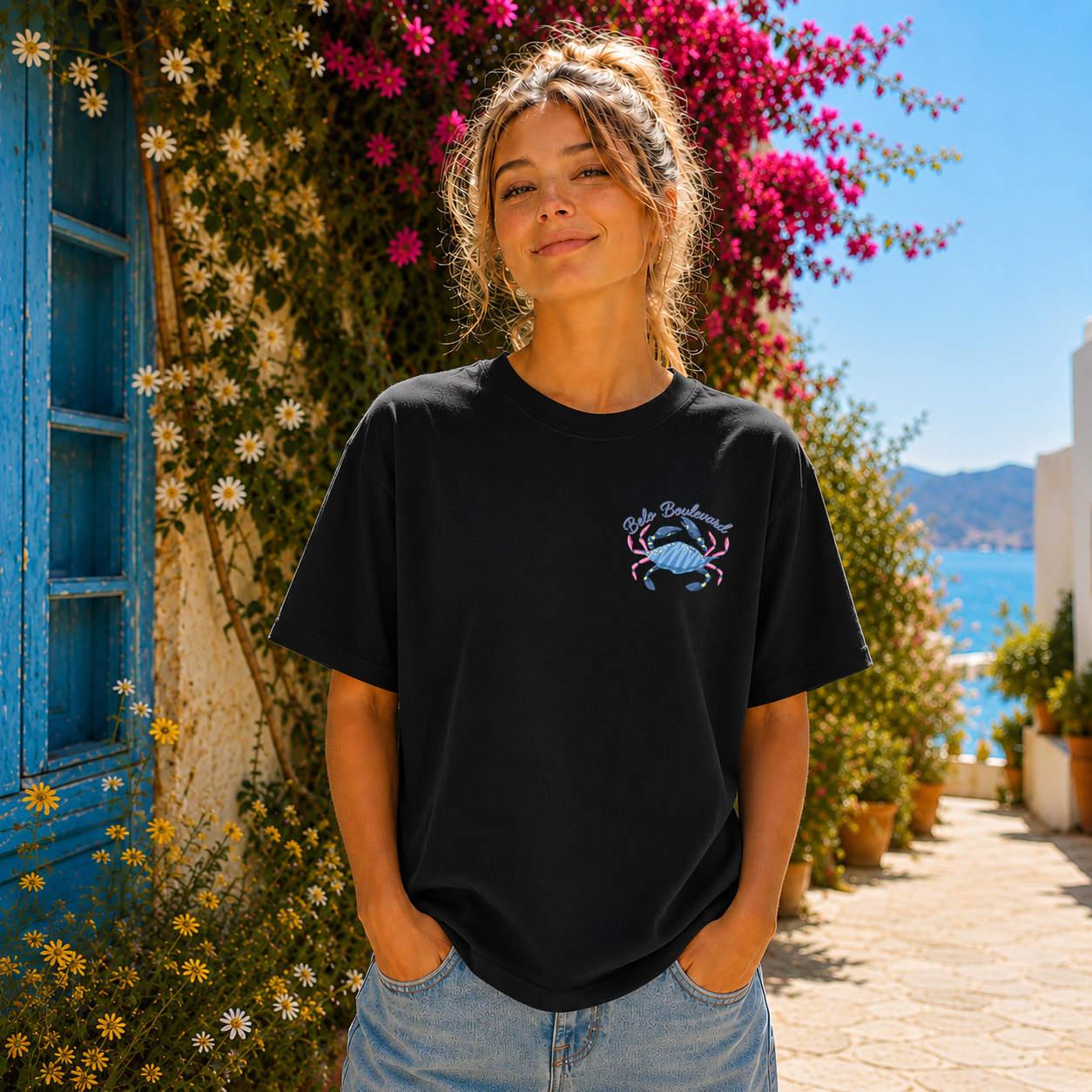 Woman wearing a black t-shirt with a blue crab design in a scenic outdoor setting.