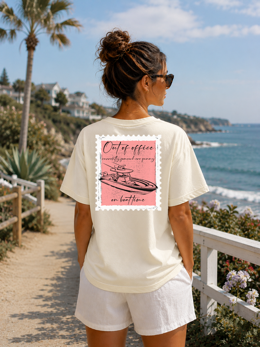 Person wearing a white t-shirt with a pink graphic design by the ocean.