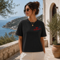 Woman wearing a black t-shirt with text, standing outdoors with scenic background