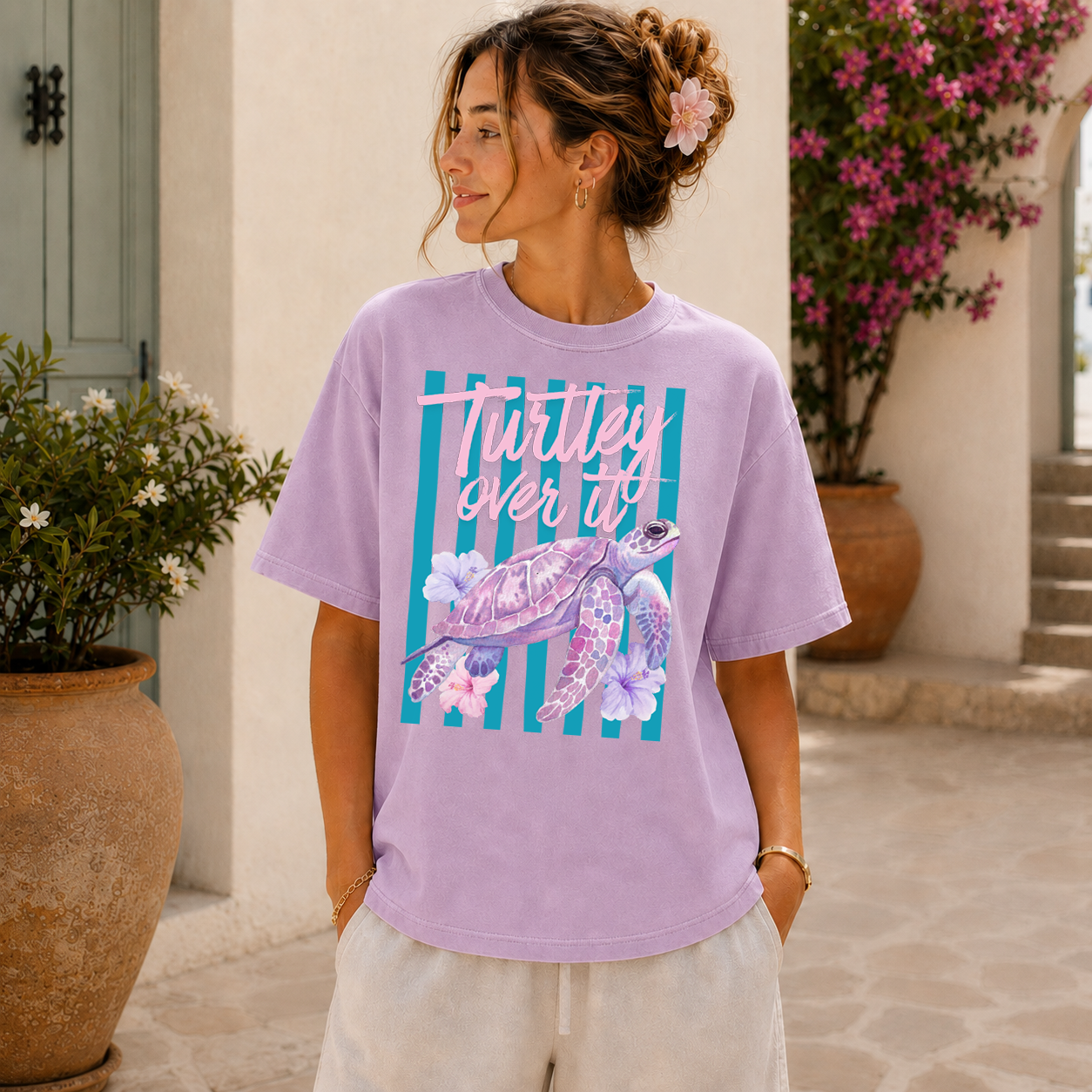 Woman wearing a purple t-shirt with a turtle graphic and text, standing outdoors.