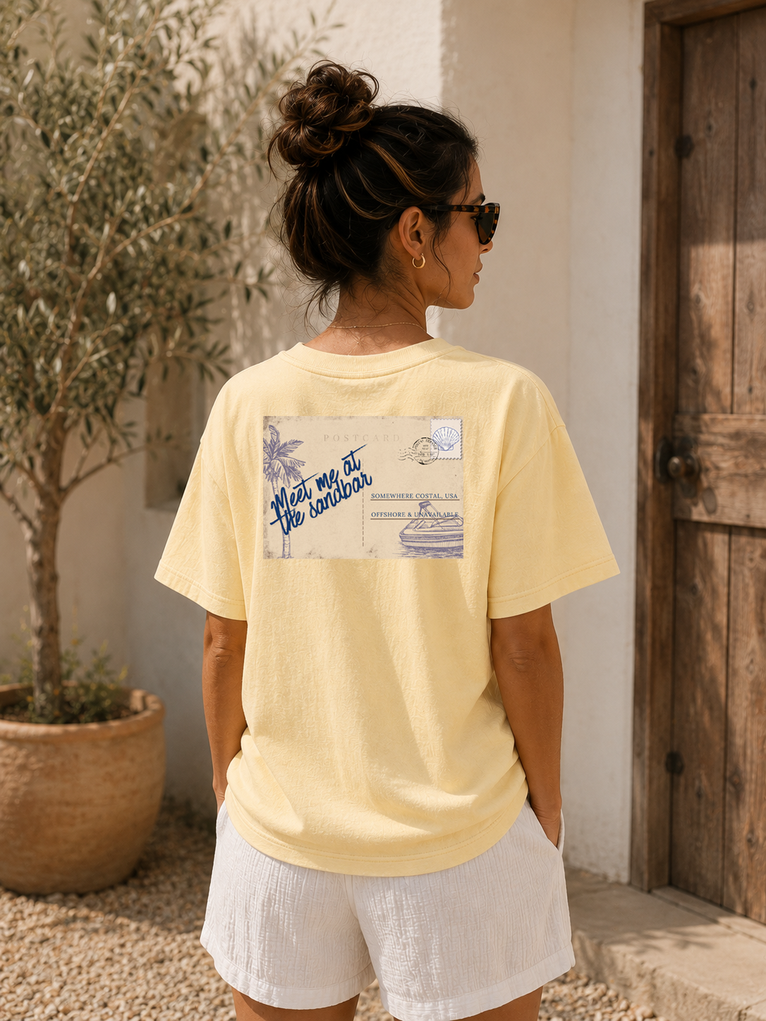 Woman wearing a yellow t-shirt with a graphic on the back, standing outdoors.